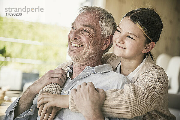 Happy senior man with granddaughter at home