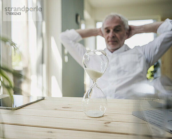 Hourglass on table with man in background at home