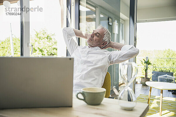 Businessman with hands behind head relaxing at home