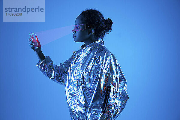 Frau mit Smart-Brille scannt futuristisches Smartphone vor blauem Hintergrund