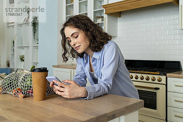 Junge Frau benutzt Smartphone am Esstisch