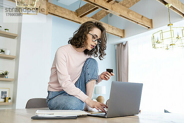 Frau macht Online-Shopping mit Kreditkarte über Laptop zu Hause