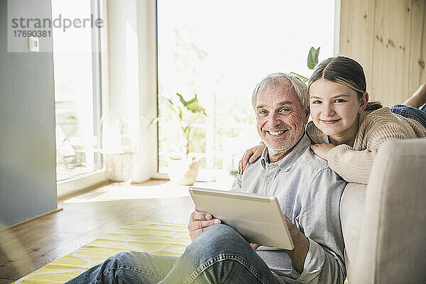 Glücklicher älterer Mann und Enkelin mit Tablet-PC zu Hause
