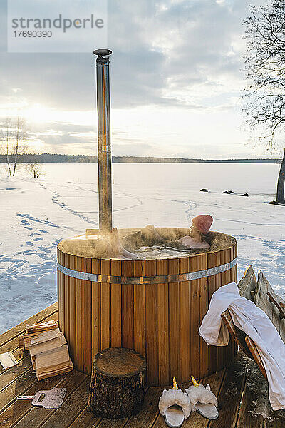 Frau nimmt im Winter bei Sonnenaufgang ein heißes Wasserbad