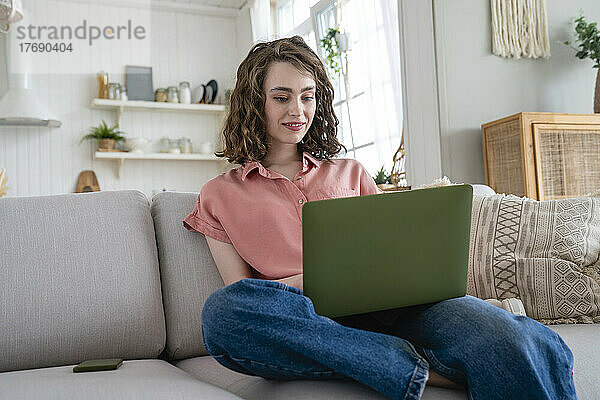 Lächelnder Freiberufler  der zu Hause am Laptop arbeitet