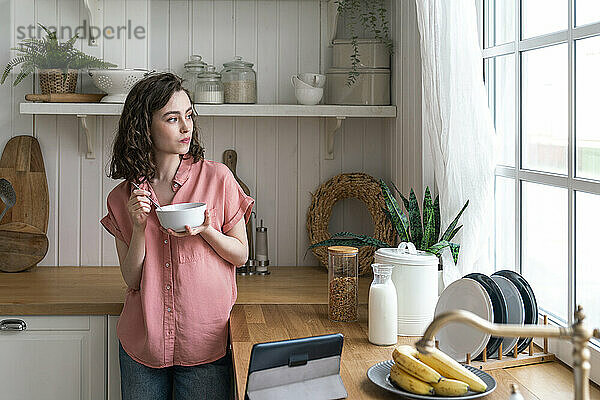 Frau frühstückt zu Hause am Küchentisch
