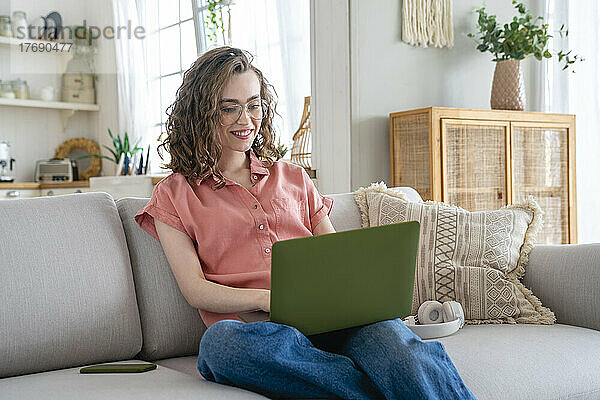 Glückliche Geschäftsfrau mit Brille  die zu Hause am Laptop arbeitet