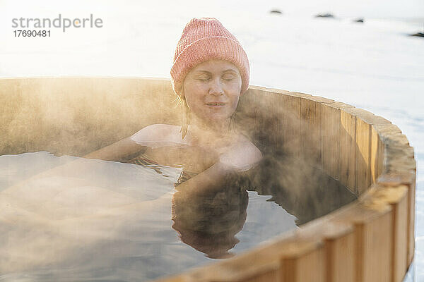 Entspannte Frau ohne Hemd genießt im Winter ein heißes Wasserbad