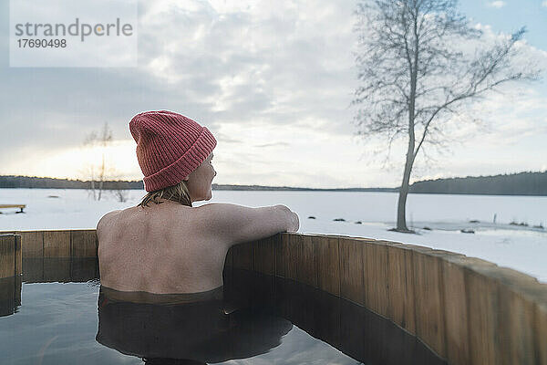 Frau genießt die Aussicht auf die Natur beim Baden im Whirlpool