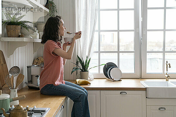Junge Frau frühstückt zu Hause in der Küche