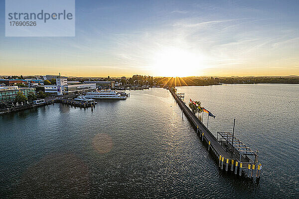 Germany  Baden-Wurttemberg  Friedrichshafen  Aerial view of town on shore of Lake Constance at sunrise with long pier in foreground