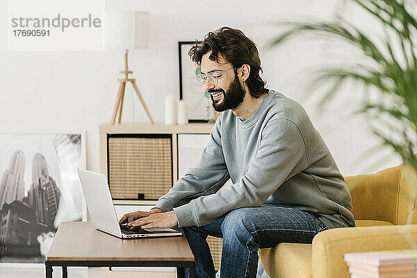 Lächelnder Mann mit Brille und Laptop zu Hause