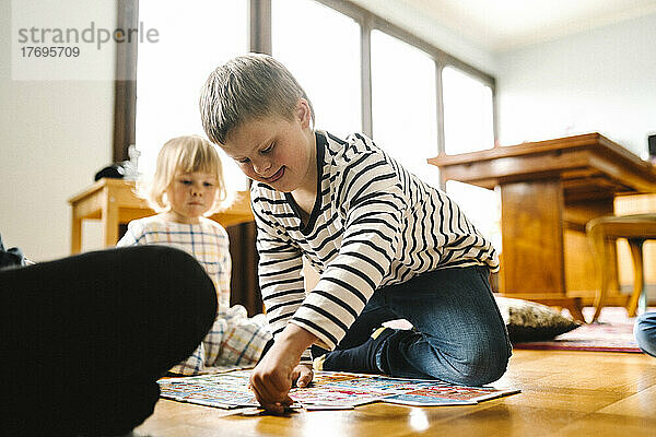 Junge mit Behinderung  der mit seinem Vater und seiner Schwester im heimischen Wohnzimmer ein Puzzle löst