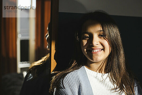 Porträt eines glücklichen Mädchens mit Sonnenlicht im Gesicht zu Hause