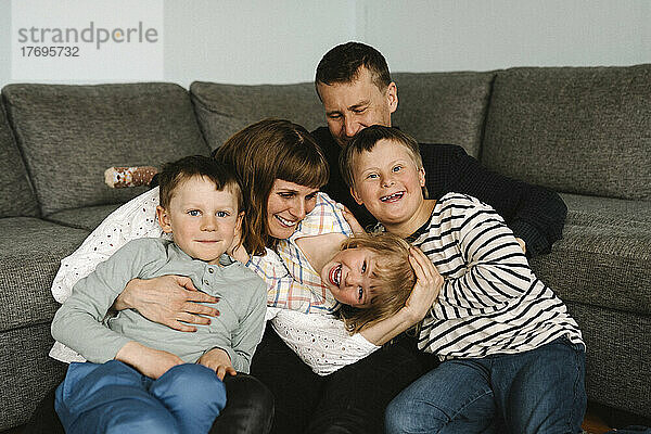 Porträt von glücklichen Kindern mit Eltern auf dem Sofa im Wohnzimmer