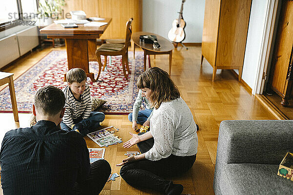 Eltern fügen Puzzleteile mit Kindern im Wohnzimmer zusammen