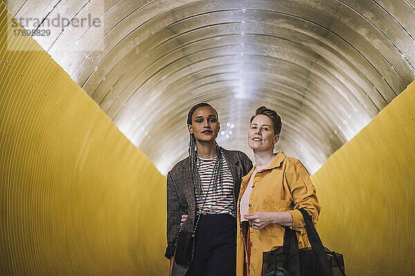 Porträt eines lesbischen Paares  das in einem beleuchteten U-Bahn-Tunnel steht