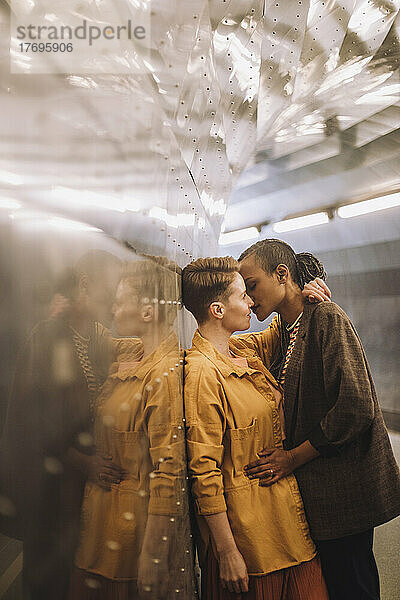 Romantische Frau umarmt und küsst Freundin in beleuchteter U-Bahn