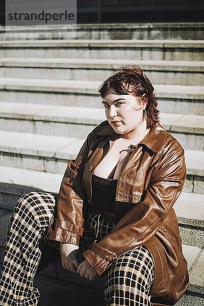 Porträt einer jungen Frau auf einer Treppe sitzend an einem sonnigen Tag