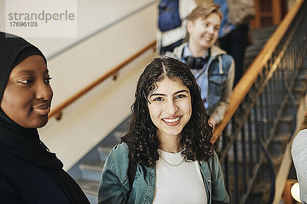 Porträt einer glücklichen Studentin mit einem Freund im Treppenhaus