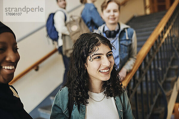 Lächelnde Studentinnen blicken auf eine Treppe in einer Universität