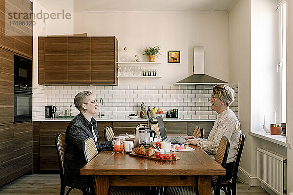 Junges lesbisches Paar  das am Esstisch in der Küche sitzt und miteinander spricht