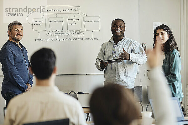 Männlicher Lehrer mit Schülern bei einer Fragestunde im Klassenzimmer