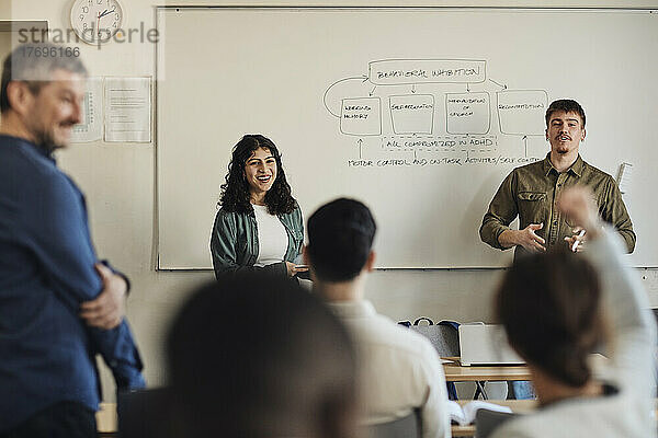 Männliche und weibliche Schüler unterhalten sich mit Freunden während einer Fragestunde im Klassenzimmer