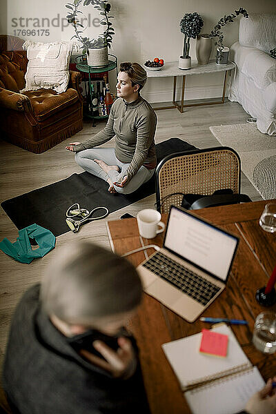 Hohe Winkel Ansicht der lesbischen Frau übt Yoga  während zu Hause sitzen