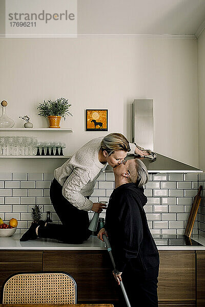 Zärtliche lesbische Frauen küssen sich beim gemeinsamen Putzen der Küche zu Hause