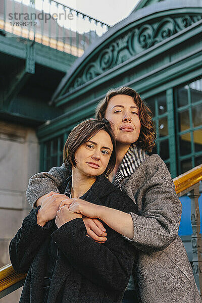 Porträt eines lesbischen Paares  das sich auf einer Treppe in der Stadt umarmt