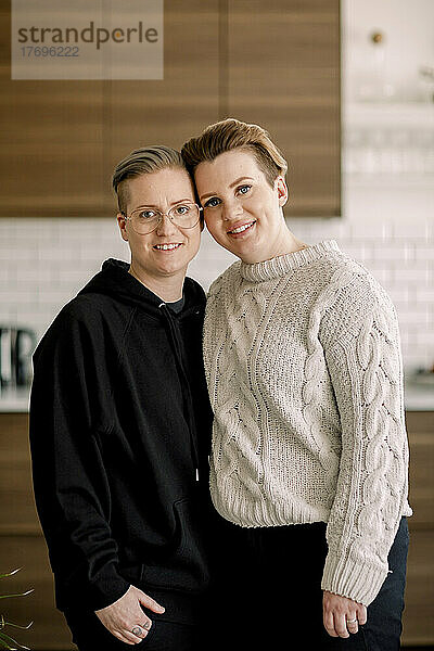 Porträt eines lächelnden jungen lesbischen Paares  das zusammen zu Hause steht