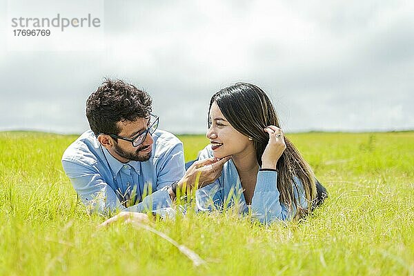 Junges verliebtes Paar  das im Gras liegt und sich gegenseitig berührt  zwei verliebte Menschen  die im Gras liegen und sich ansehen  Ein Paar  das im Gras liegt und sich ansieht