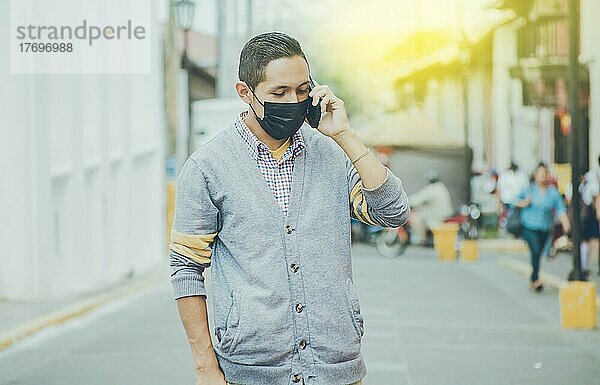 Mann mit chirurgischer Maske am Telefon  lateinischer Mann mit Maske am Telefon auf der Straße  Mann mit Maske am Telefon auf der Straße