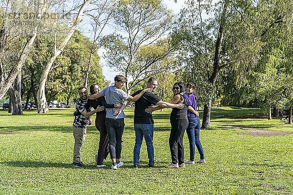 Multi ethnische Familie Gruppe zu Fuß Arm in Arm in einem Park  Blick in die Kamera lächelnd  glückliche Haltung. Familie  Gruppe  Teamarbeit  Freundschaft Konzept