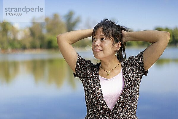 Porträt einer jungen lateinischen Frau mit Blick zur Seite  auf einen See mit Kopierraum