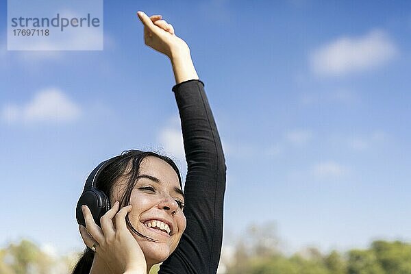Junge Frau  die im Freien mit Kopfhörern Musik hört. Ausdruck von Glück  gewinnende Einstellung. Textfreiraum