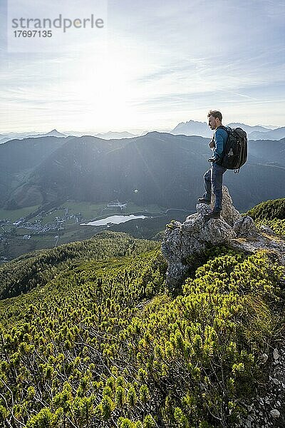 Wanderer steht auf einem Felsen zwischen Latschenkiefern  Blick auf Berglandschaft mit Pillersee  Abstieg vom Heimkehrerkreuz  Nuaracher Höhenweg  Loferer Steinberge  Tirol  Österreich  Europa