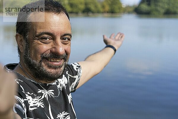 Aktiver gutaussehender reifer kaukasischer Mann  der ein Selfie macht und sich an einem See zeigt. Outdoor-Abenteuer-Konzept