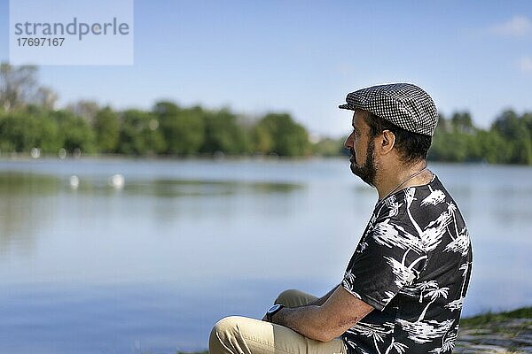 Porträt eines Mannes  der entspannt sitzt und über einen See nachdenkt. Leerzeichen kopieren