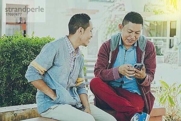 Mann zeigt sein Handy einem anderen Mann  zwei Männer überprüfen ihre Handys  Zwei junge Männer vergleichen ihre Handys