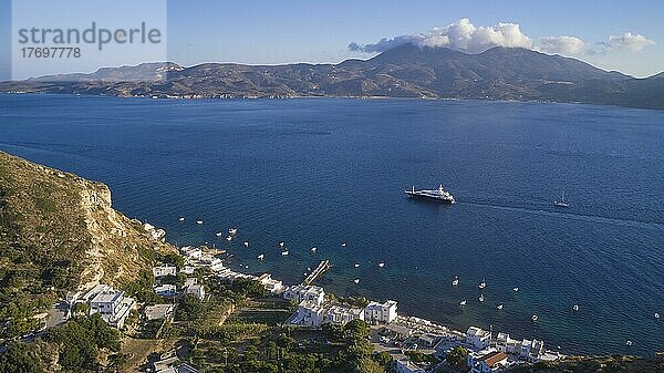 Boote  Häuser am Meer  Berg Profitis Elias  Luxusyacht  hellblauer Himmel  weiße Haufenwolken über Gebirge  Golf von Milos  Insel Milos  Kykladen  Griechenland  Europa