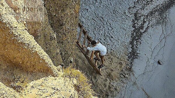Tourist beim Abstieg von Leiter  Felsenbucht  bunte Lavafelsen  Tsigrado Beach  Insel Milos  Kykladen  Griechenland  Europa