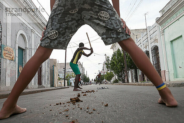 Mehrere junge Männer spielen Baseball in den Straßen von Cienfuegos; Cienfuegos  Kuba