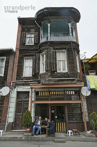 Eine Gruppe von Männern sitzt vor einem dreistöckigen Wohnhaus; Istanbul  Türkei