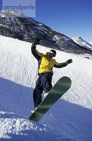 Mann springt auf Snowboard in den Alpen