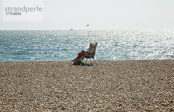 Sitzen auf einem Strandstuhl am Rande des Wassers; Seaford  East Sussex  England