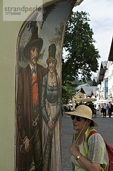 Touristen gehen an einer Wandmalerei in einem traditionellen Bekleidungsgeschäft in Kitzbühel vorbei. Kitzbühel