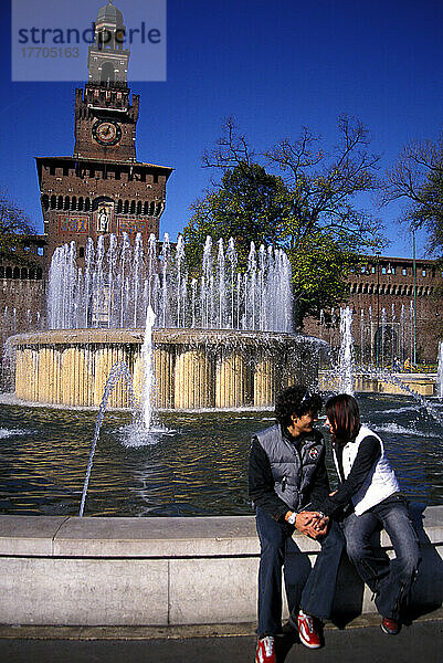 Junges Paar sitzt neben einem Brunnen am Castello Sforzesco  hält Händchen  Liebe  Romantik. Mailand  Italien