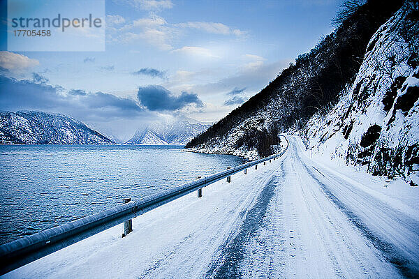 Tückische  eisige Straße  die sich um den Berghang und das Fjordufer windet  mit dramatischer Aussicht auf die Berge; Ortnevik  Sognefjord  Norwegen